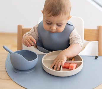 Baby eating watermelon with mess-free silicone placemat and divided plate, easy clean food catcher for mealtime