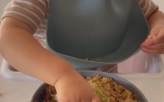 Toddler eating rice and veggies with bib, mess-free mealtime solution