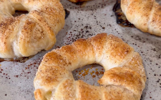 Freshly baked cinnamon sugar bagels on parchment paper, golden brown and flaky