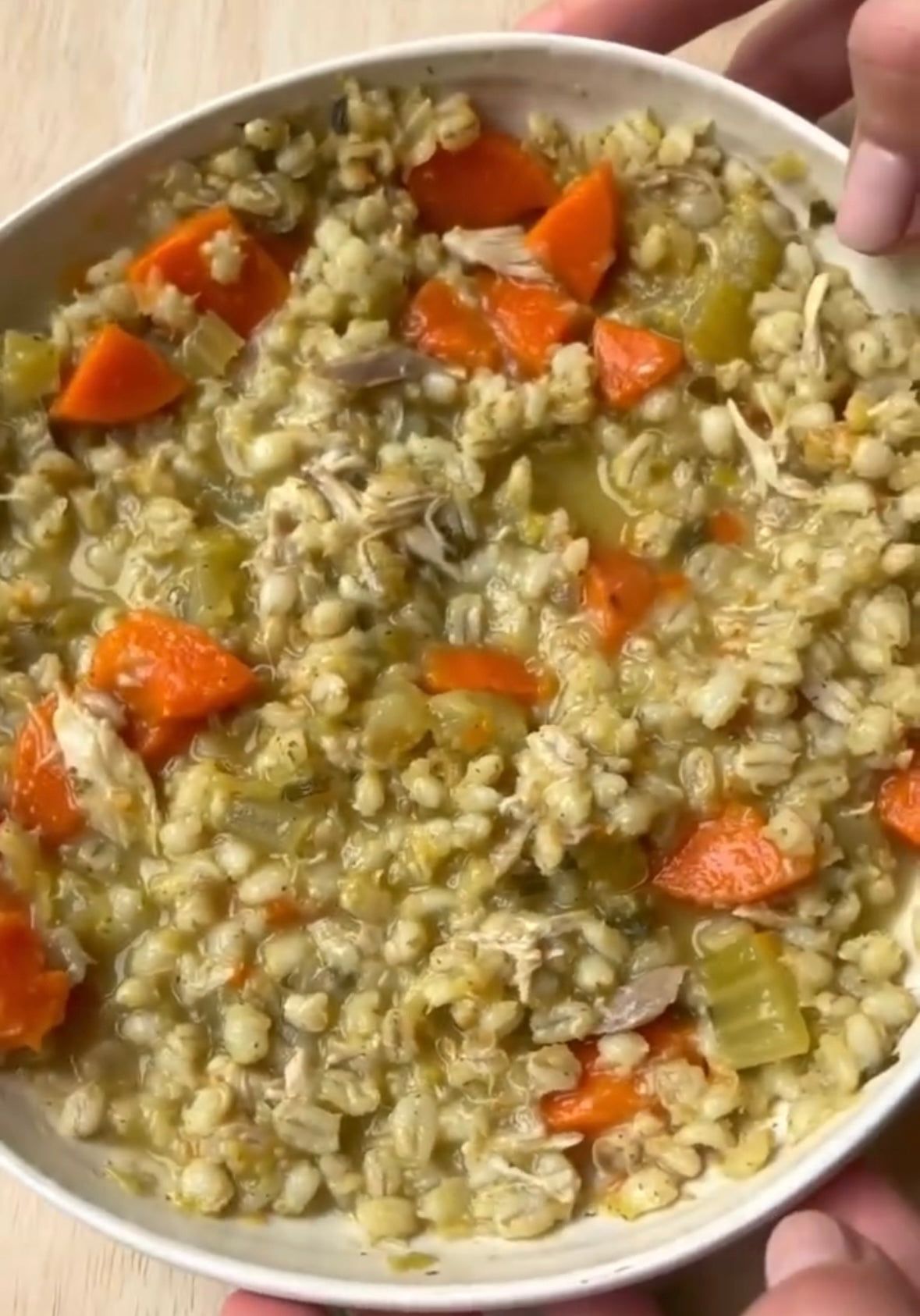 Hearty chicken barley soup with carrots and celery in a white bowl, perfect for mess-free meals.