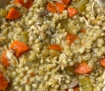Hearty chicken barley soup with carrots and celery in a white bowl, perfect for mess-free meals.